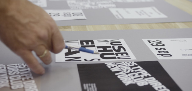 Person zeigt mit Stift auf typografische Entwürfe