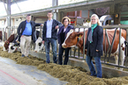 Die vier Personen stehen neben Kühen im Stall.